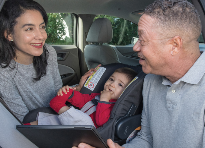 A Child Passenger Safety Technician is pictured here working with an elderly caregiver and an infant.