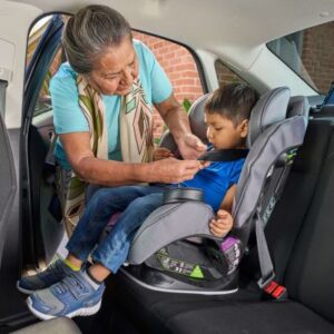 A Native American works to ensure this child is properly restrained in his car seat.