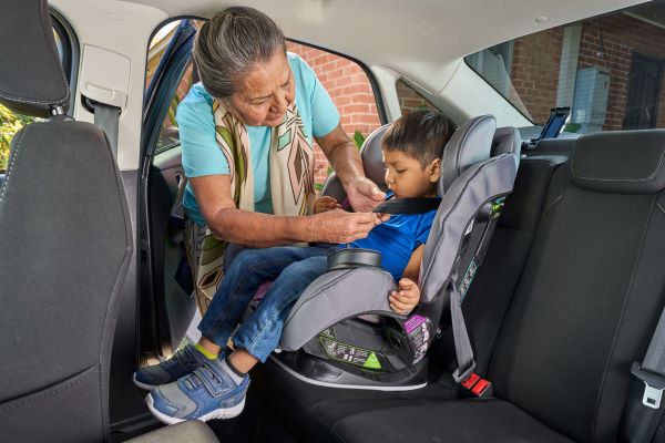 A Native American works to ensure this child is properly restrained in his car seat.