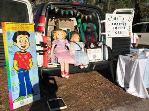 The back doors of a van are open showcasing resources assembled for a car seat checkup event.