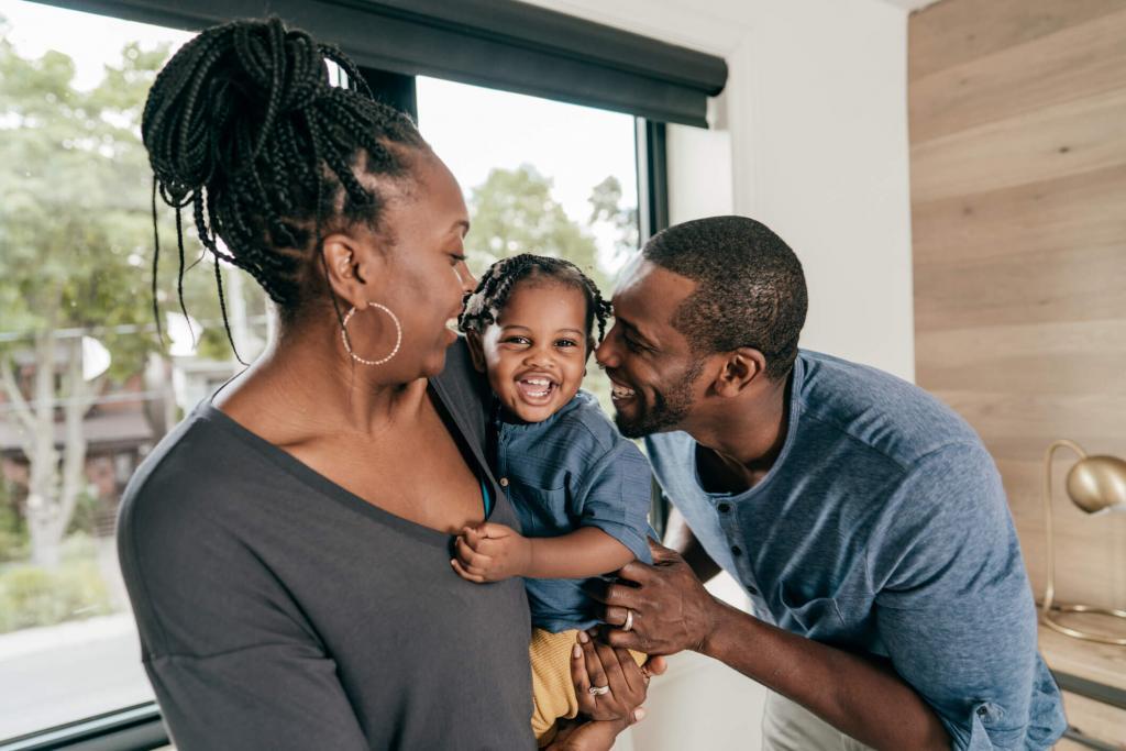 A mom holds her child, while dad snuggles in during a playful moment at home.