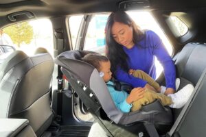 A Child Passenger Safety Technician is pictured here securing a little one in a car seat.